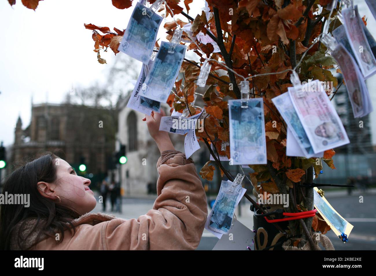 Une femme regarde les billets de 350m de la « Bank of Brexitlies » portant la face du Premier ministre Boris Johnson et du principal député Brexiteer Jacob Rees-Mogg attaché à un « money Tree » établi par des militants anti-Brexit devant le Parlement à Londres, en Angleterre, sur 7 janvier 2020. Lors de la campagne du référendum de 2016, les sortants ont faussement affirmé que 350m étaient envoyés chaque semaine dans l'UE, ce qui pourrait être dépensé au service national de santé. Le Royaume-Uni est prévu de quitter l'UE à 11pm heures sur 31 janvier, début d'une période de transition qui s'étend jusqu'à la fin de l'année, à l'époque où le Premier ministre Boris Banque D'Images