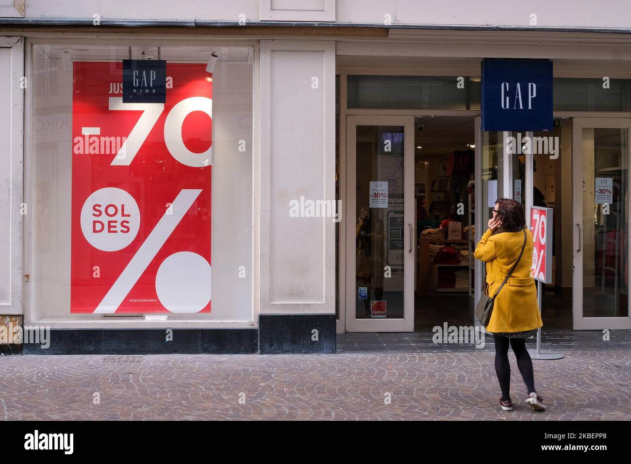 Une femme regarde une boutique de vêtements annonçant des ventes sur 7  janvier 2020 à Lille, France. À la suite d'un décret du ministère de  l'économie et des finances en mai 2019,