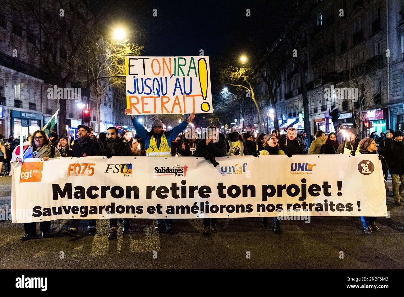 Les manifestants défilent derrière une bannière qui se lit comme suit : « Macron retire ton projet ! Épargnons et améliorons nos pensions" jeudi 23rd janvier 2020, quelques centaines d'opposants à la réforme des pensions, syndicalistes, blousons jaunes, enseignants, cheminots, etc., A participé à une marche torchlight à Paris entre la place de la Nation et la place de la République, répondant à un appel de plusieurs syndicats à dire non à la réforme des retraites. (Photo de Samuel Boivin/NurPhoto) Banque D'Images