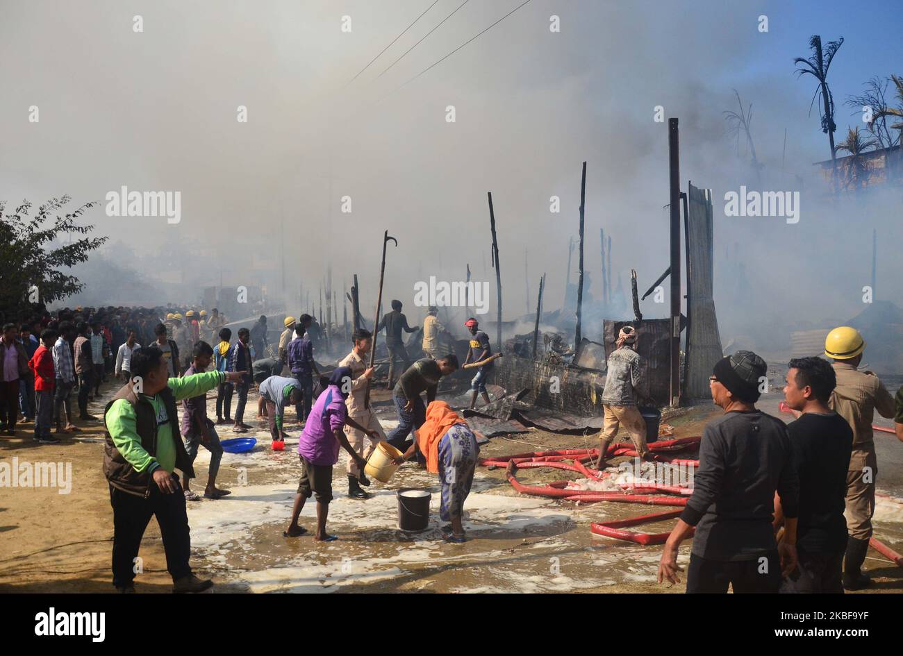 Un pompier et des résidents vaporisent de l'eau pour éteindre un incendie qui a éclaté au camp de Birmanie à Dimapur, dans l'État du Nagaland, au nord-est de l'Inde, qui a brûlé une maison d'ustensiles et 4 maisons résidentielles à 25 janvier 2020. (Photo de Caisii Mao/NurPhoto) Banque D'Images