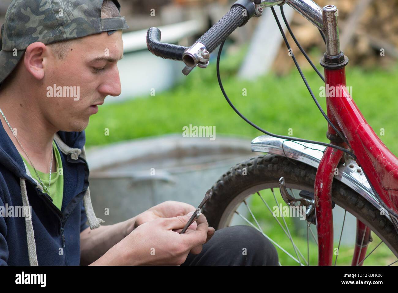 jeune maître assis près d'un vélo cassé et pense Banque D'Images