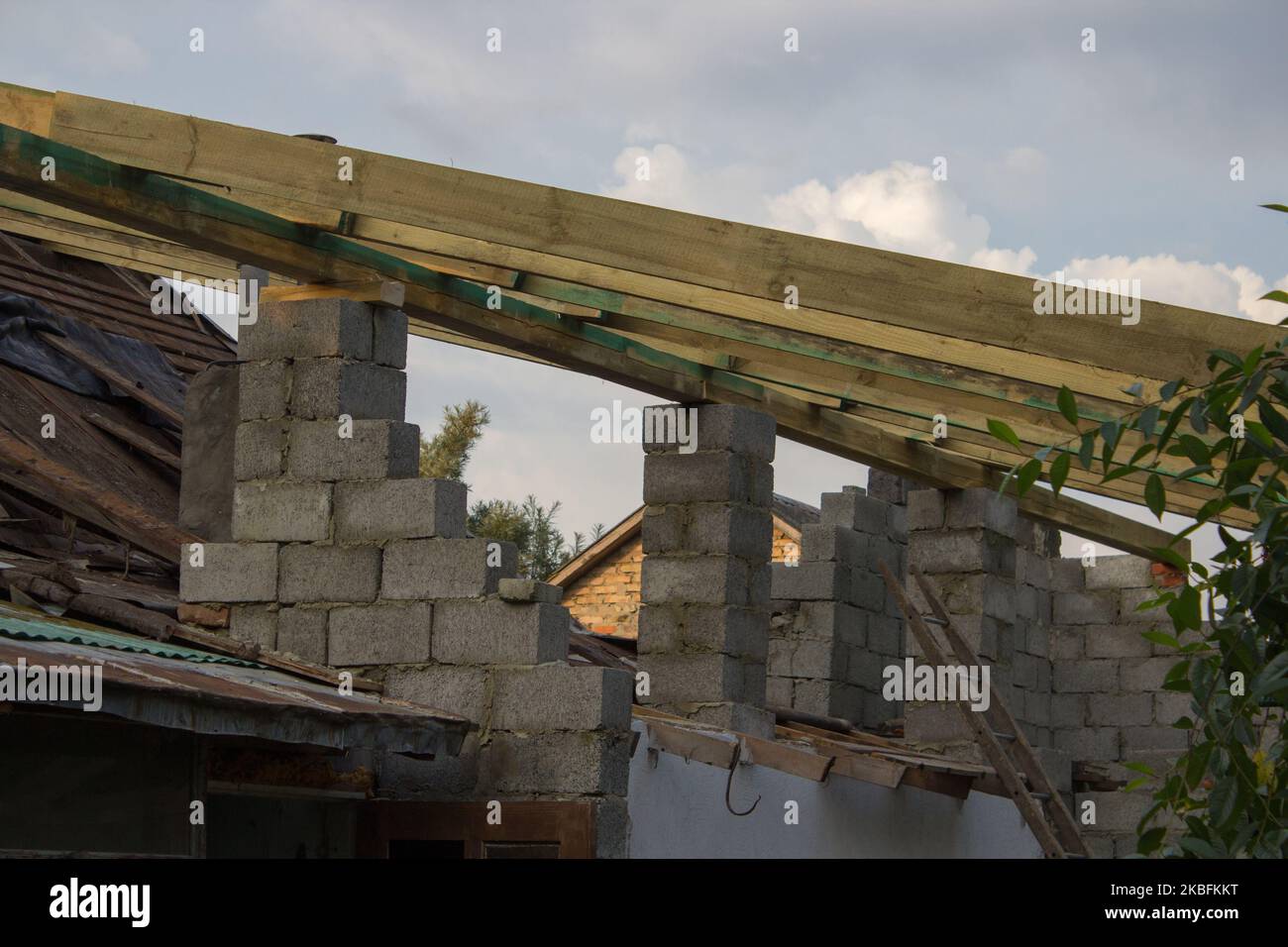 Une nouvelle construction de toit avec un cadre de treillis en bois faisant un sommet contre un ciel bleu avec des nuages. Banque D'Images