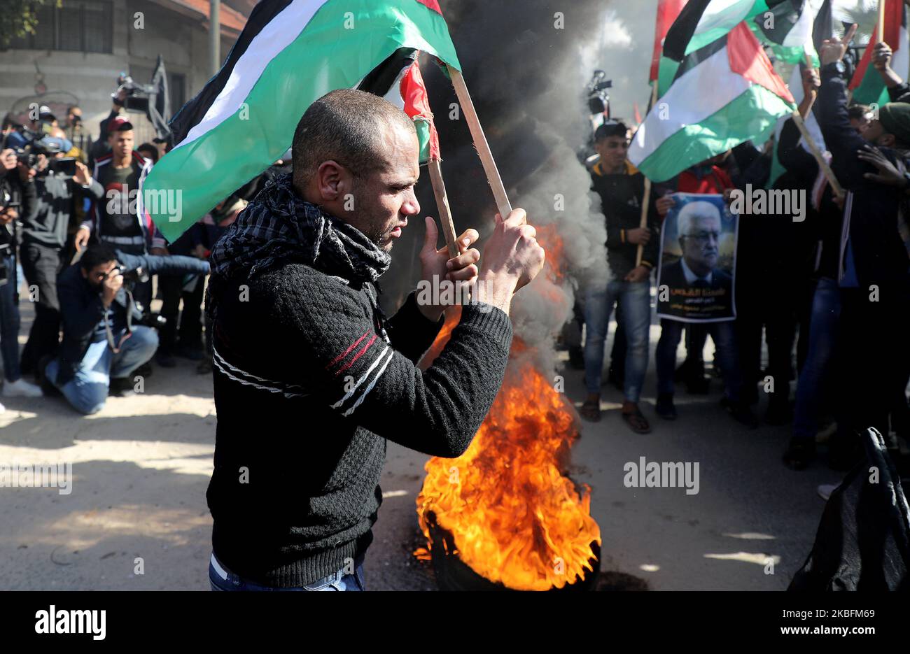 Les manifestants palestiniens brandent des slogans et brandent les drapeaux palestiniens alors qu'ils se mettent à flammer des pneus lors d'une protestation contre la proposition de plan de paix attendue par le président américain Donald Trump à Gaza sur 28 janvier 2020. (Photo de Majdi Fathi/NurPhoto) Banque D'Images