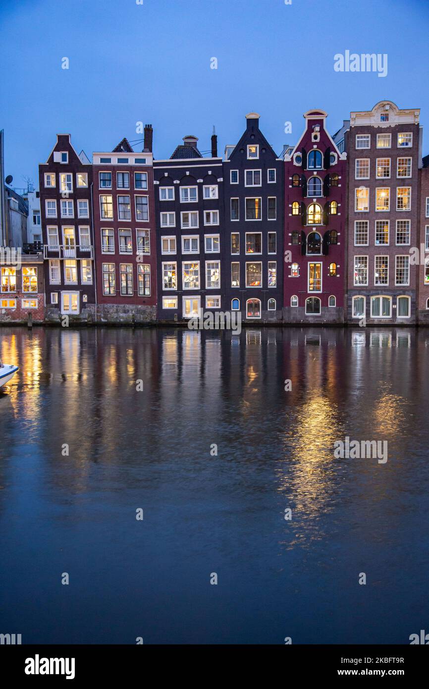 Les célèbres maisons de danse colorées à l'architecture hollandaise authentique, bordant des bâtiments traditionnels avec des lumières. Les maisons éclairées sur l'eau au bassin du canal de Damrak sont une attraction touristique célèbre, un point de repère près de la gare centrale, une attraction touristique importante, à Amsterdam, Hollande, pays-Bas comme vu après le coucher du soleil, pendant la magie bleue heure, le crépuscule et la nuit. Amsterdam, pays-Bas (photo de Nicolas Economou/NurPhoto) Banque D'Images