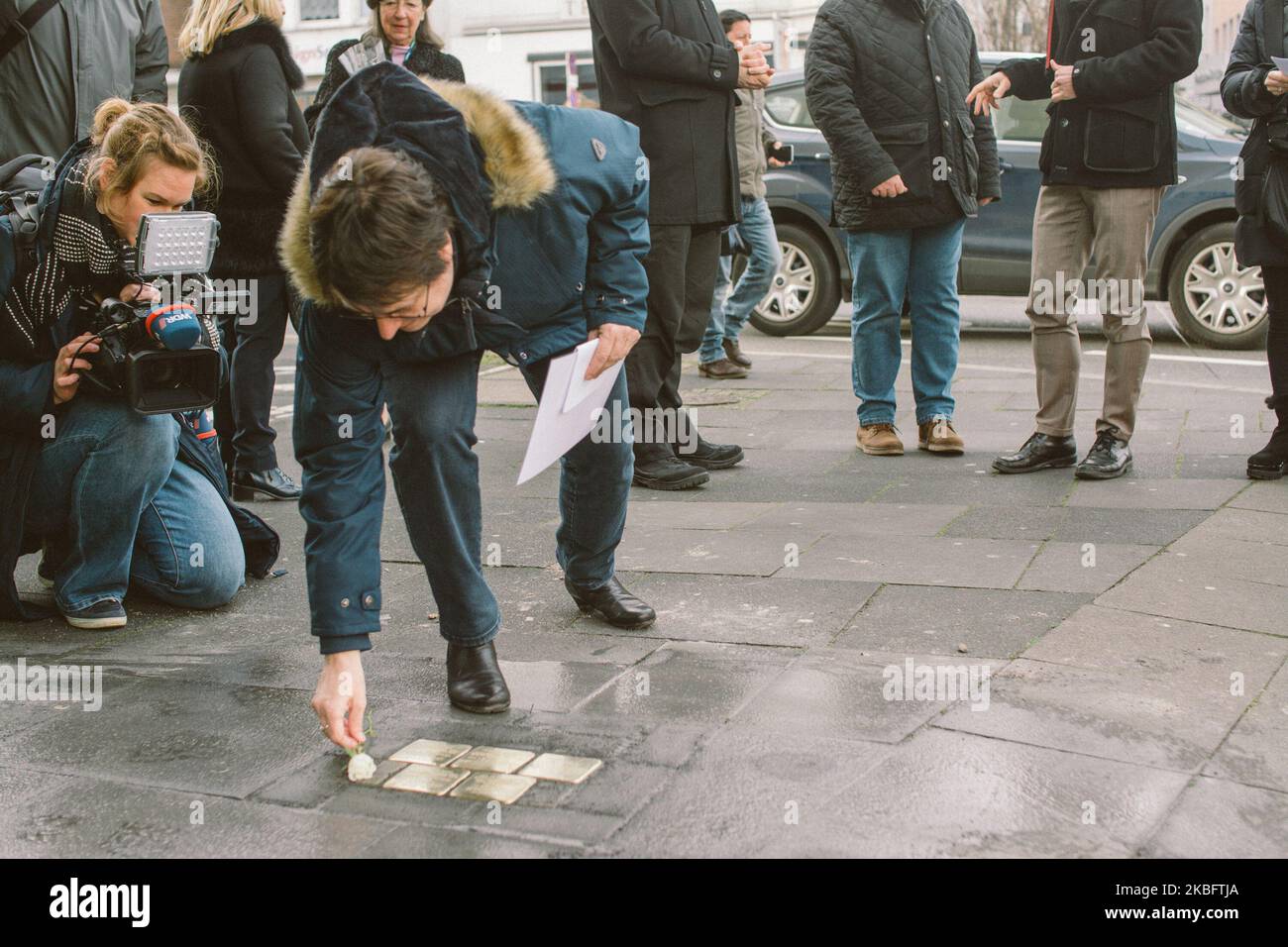Une femme pose une rose blanche sur la chaussée après l'installation