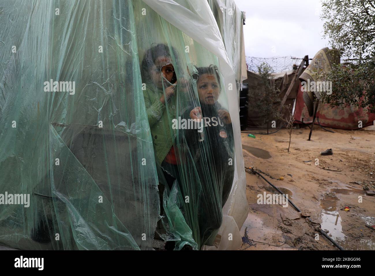Les enfants palestiniens regardent la pluie derrière des feuilles de nylon couvrant leur tente familiale, lors d'un jour pluvieux dans le quartier d'al-Amal (l'espoir en arabe) de Beit Lahia, dans le nord de la bande de Gaza, sur 8 février 2020 . (Photo de Majdi Fathi/NurPhoto) Banque D'Images