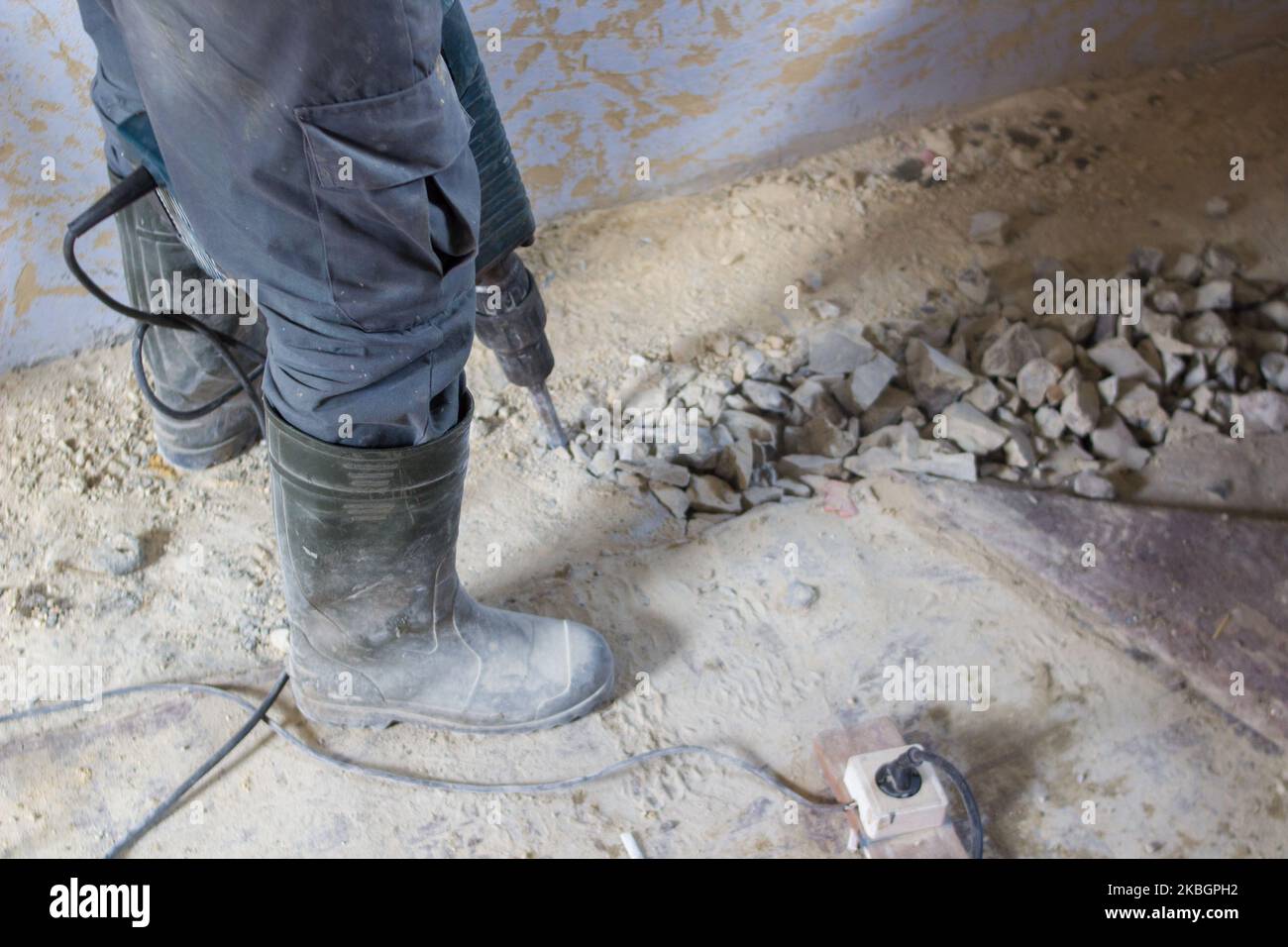 Percer un trou dans le plancher de ciment sur le chantier de construction Banque D'Images