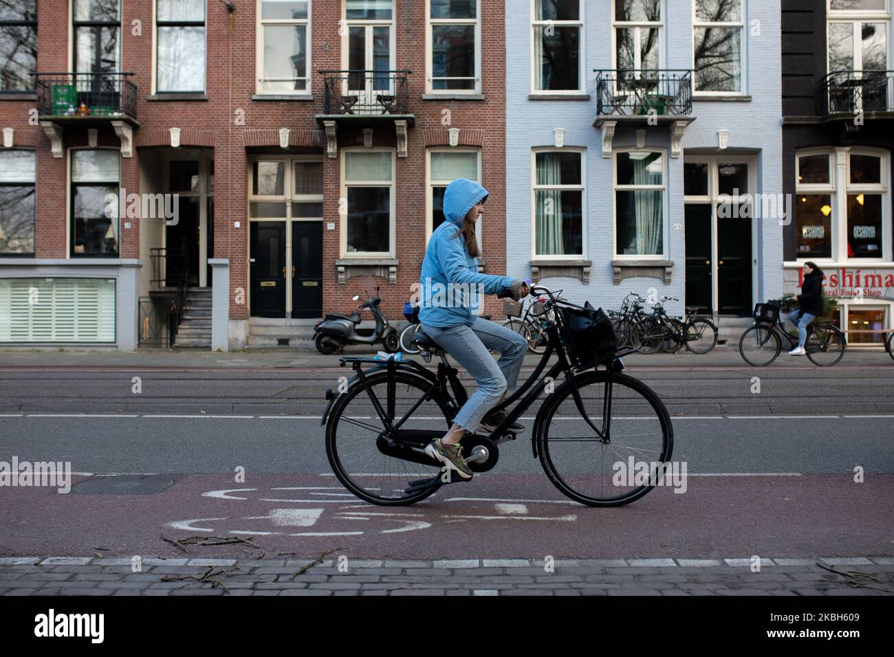 Les personnes utilisant des vélos dans la ville et/ou des stations de recharge de voiture électrique à Amsterdam vu sur 17 février 2019. Amsterdam est équipé d'un large réseau de pistes cyclables, si sûr et confortable que même les tout-petits et les personnes âgées utilisent les vélos comme mode de transport le plus facile. Les vélos sont couramment utilisés dans d'autres villes comme la Haye et Rotterdam. Les voitures et motos fonctionnant à l'essence et au diesel seront interdites d'Amsterdam à partir de 2030 dans le but de nettoyer l'air de la ville, a déclaré le conseil de la capitale néerlandaise en 2019. L'utilisation de véhicules électriques est en augmentation dans la ville. Une passe est nécessaire pour charger Banque D'Images