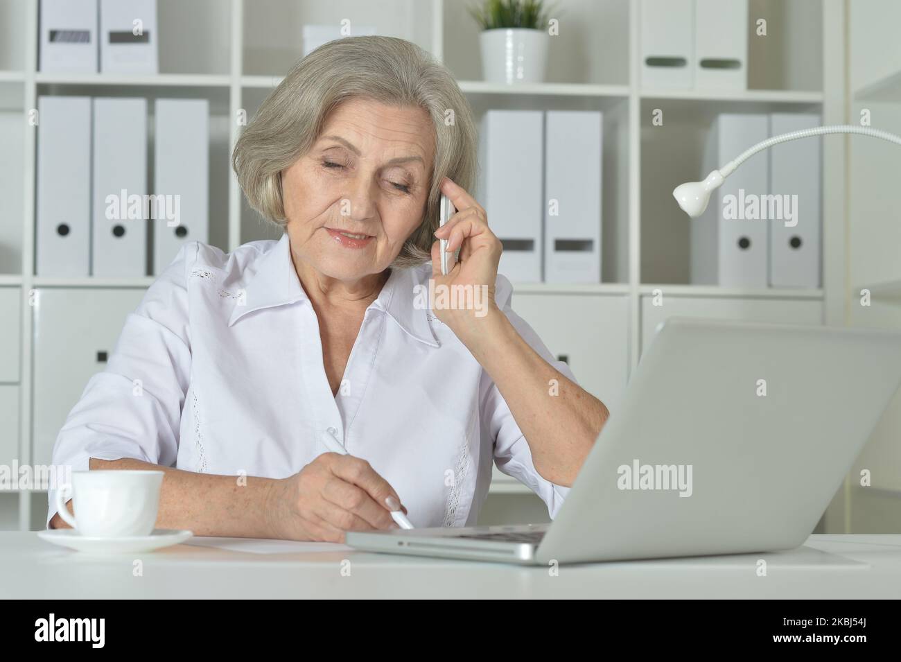 Femme âgée dans un casque suivre un cours en ligne sur ordinateur à la maison. Banque D'Images