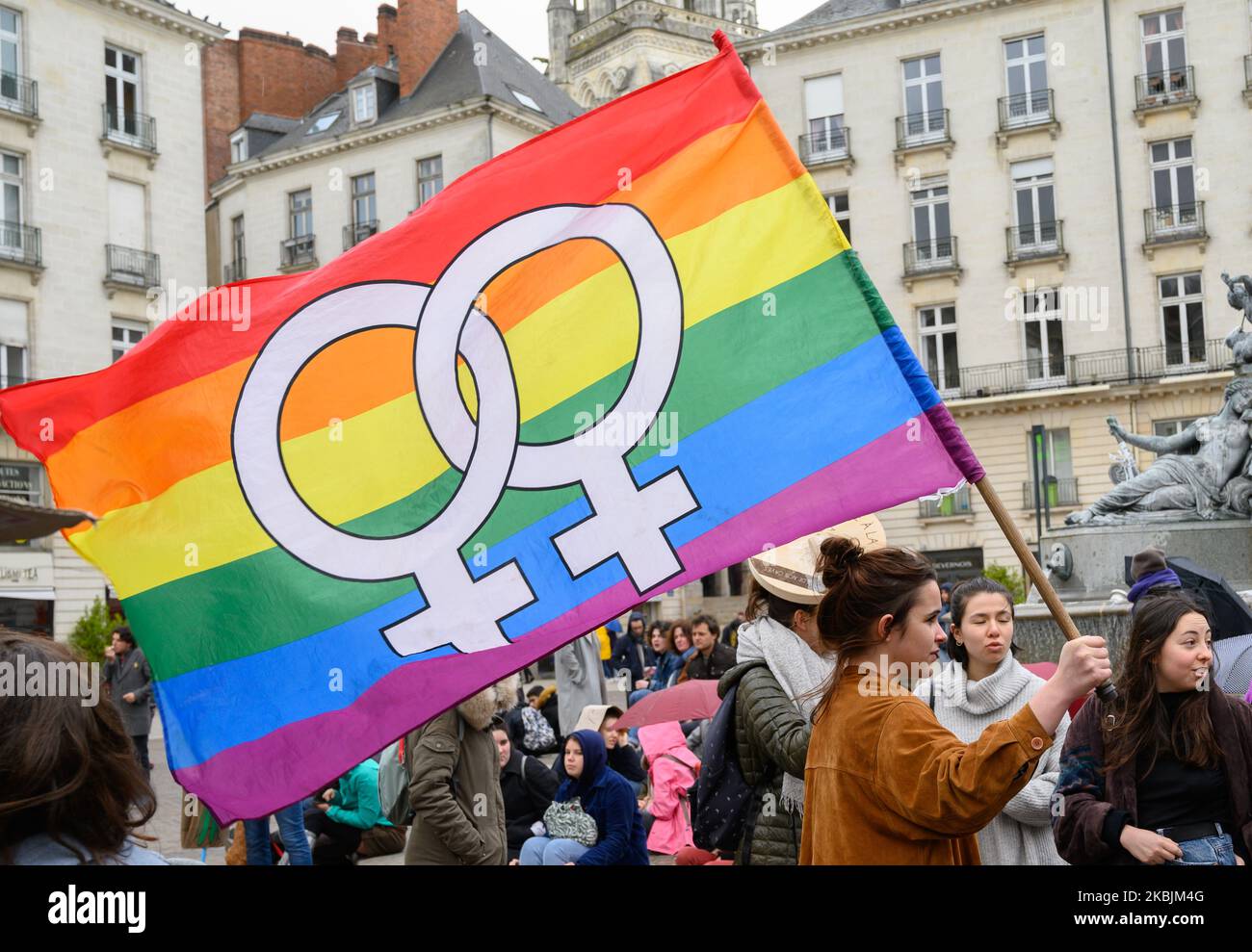 Jeune femme qui tient le drapeau de la communauté LGBTI lors de la manifestation organisée à l'occasion de la Journée internationale des droits de la femme sur le 8 mars 2020 à Nantes, France. (Photo par Estelle Ruiz/NurPhoto) Banque D'Images