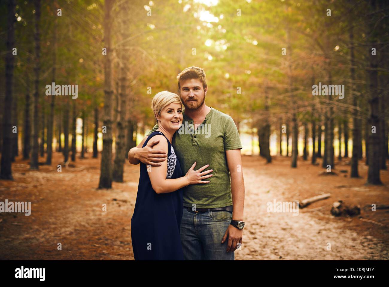 Les enfants heureux sont des parents heureux. Un couple aimant s'embrassant dans un câlin tout en se tenant dehors dans les bois. Banque D'Images