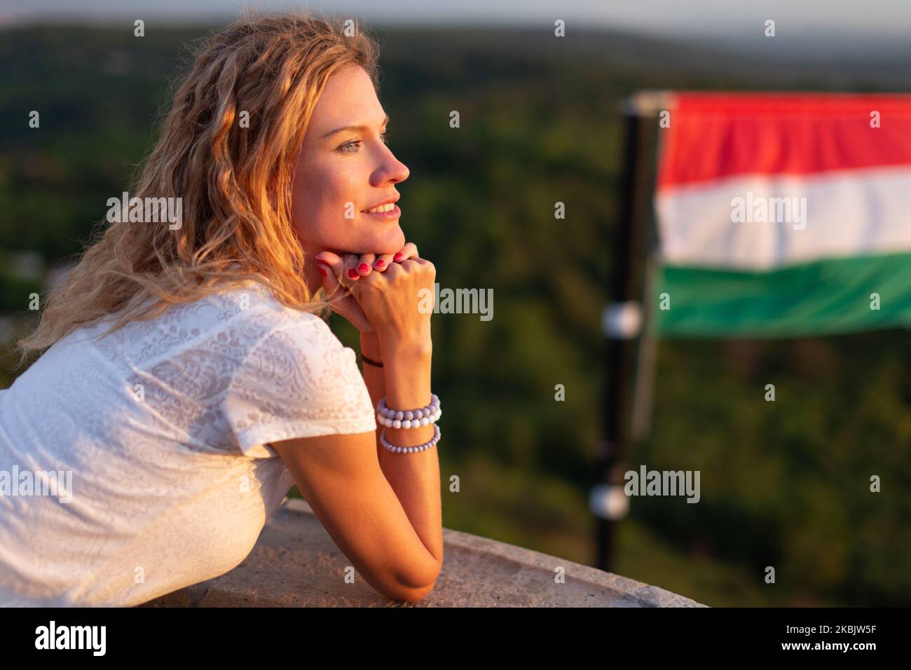 Jeune femme caucasienne joyeuse regardant la distance dans la nature au drapeau hongrois, Hongrie Banque D'Images
