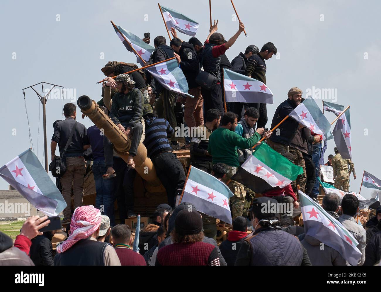 Les Syriens en train de protester montent au sommet d'un char militaire turc de M60T et d'un véhicule de combat d'infanterie (IFV) alors qu'ils tentent de bloquer la circulation sur l'autoroute de M4, qui relie les provinces du nord de la Syrie d'Alep et de Latakia, avant de nouvelles patrouilles militaires turques et russes (conformément à un accord de cessez-le-feu conclu précédemment) Dans le village d'al-Nayrab, à environ 14 kilomètres au sud-est de la ville d'Idlib et à sept kilomètres à l'ouest de Saraqib, dans le nord-ouest de la Syrie, sur 15 mars 2020. (Photo par Karam Almasri/NurPhoto) Banque D'Images