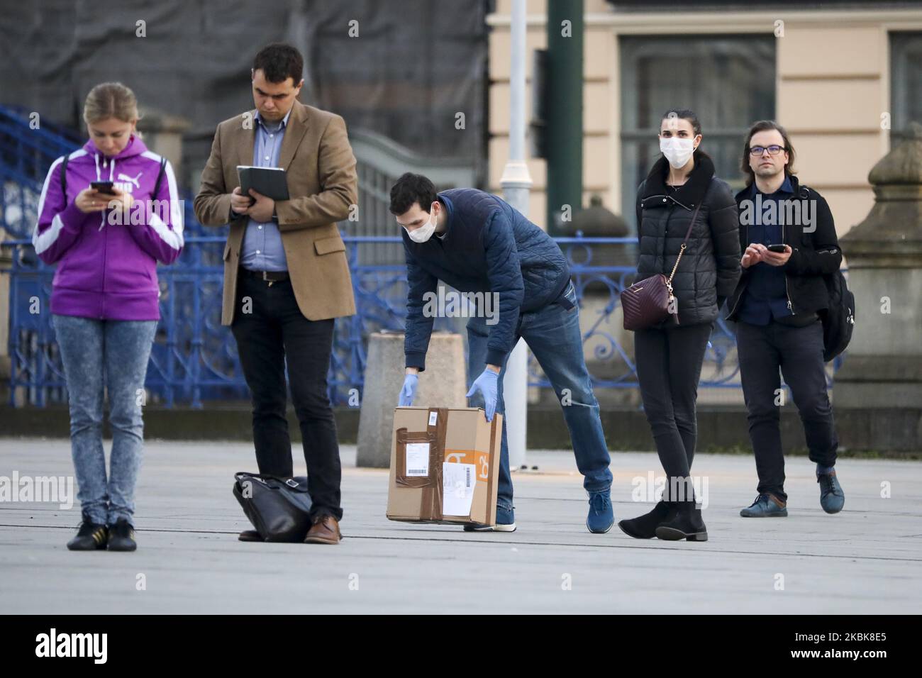 Les gens font la queue en gardant une distance de sécurité tout en attendant d'entrer dans un bureau de poste à Cracovie, en Pologne sur 19 mars 2020. En raison de la propagation du coronavirus, le Premier ministre polonais a instauré l'état d'urgence, qui comprend la fermeture d'écoles et d'universités, des contrôles aux frontières du pays et des restrictions imposées aux services tels que les musées, les restaurants, les pubs et les centres commerciaux. (Photo de Beata Zawrzel/NurPhoto) Banque D'Images