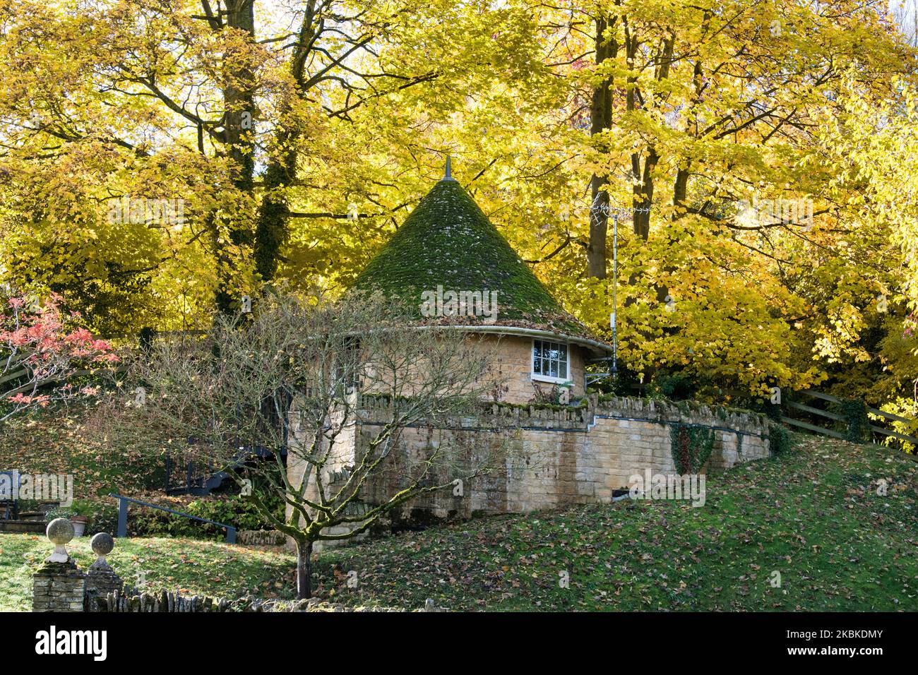Arbres d'automne et maison ronde. Buckland, Gloucestershire, Cotswolds, Angleterre Banque D'Images