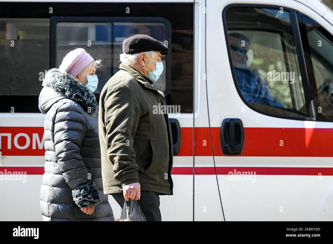 Personnes dans des masques de protection comme mesure préventive contre le coronavirus COVID-19 marchant près d'une voiture d'ambulance dans la rue à Kiev, Ukraine sur 03 avril 2020 (photo de Maxym Marusenko/NurPhoto) Banque D'Images