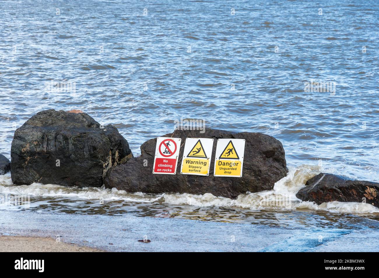 Rochers sur le bord non surveillé de la parade sur le mur de mer avec des panneaux d'avertissement Lowestoft suffolk 2022 Banque D'Images