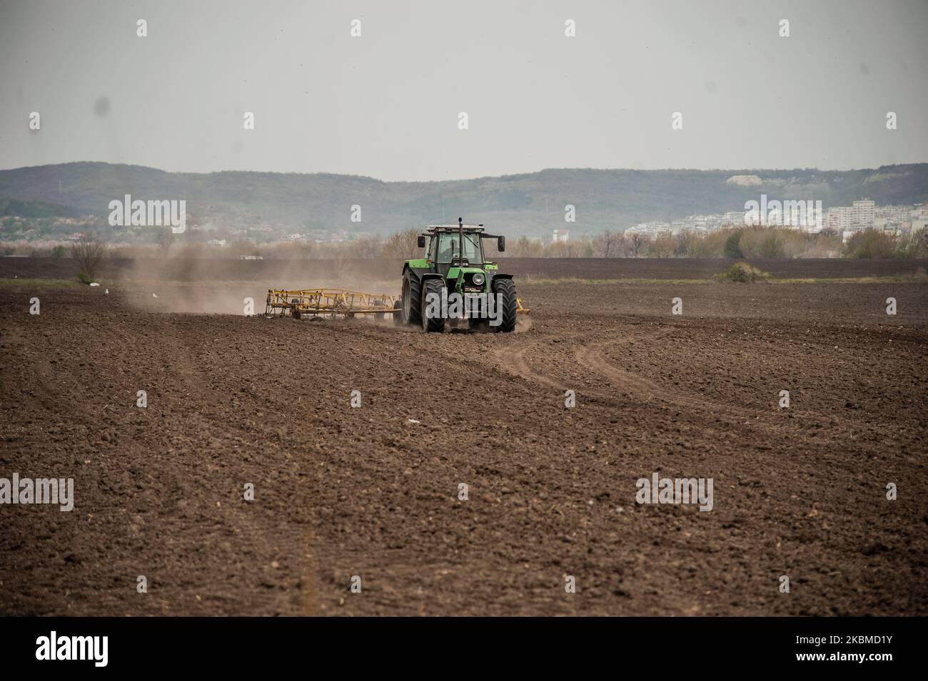 On voit un tracteur travailler sur un champ près du village de Topoli, en Bulgarie, sur 14 avril 2020. Le gouvernement bulgare ferme les marchés des produits frais du jeudi 16th au dimanche 19th, lorsque les chrétiens orthodoxes célébreront Pâques. Les marchés ont été fermés à titre de mesure contre Covid-19 et ouverts à nouveau, ce qui a entraîné des rassemblements de masse. Le gouvernement les ferme maintenant. Cependant, cela ne s'appliquera pas aux grandes chaînes d'hypermarché qui dérange de nombreux agriculteurs locaux - leurs produits se termineront dans la benne à ordures tandis que les gens achètent des légumes importés. En réponse à ces préoccupations, le gouvernement a dédamié Banque D'Images