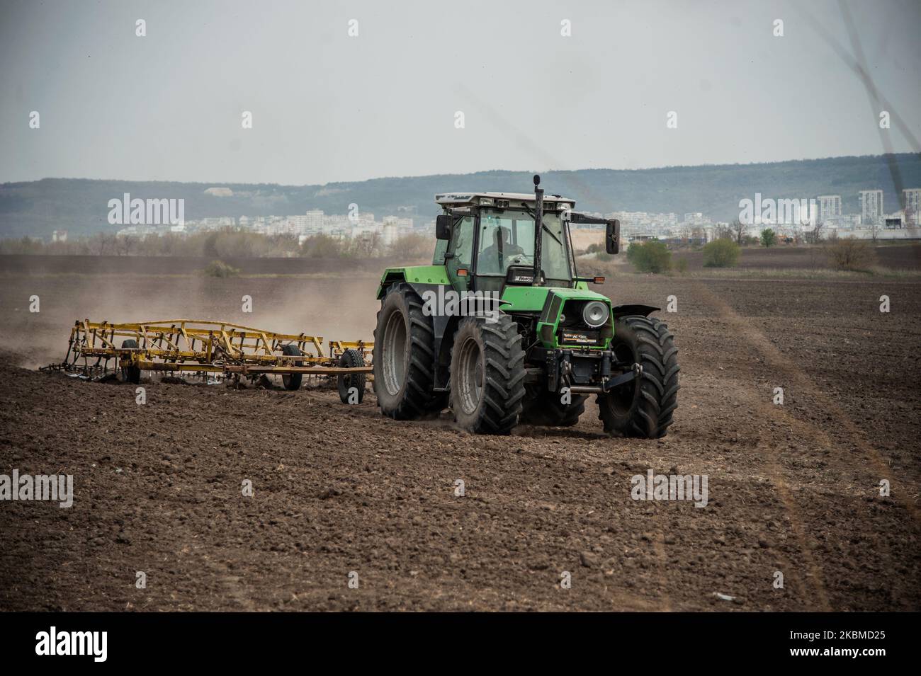 On voit un tracteur travailler sur un champ près du village de Topoli, en Bulgarie, sur 14 avril 2020. Le gouvernement bulgare ferme les marchés des produits frais du jeudi 16th au dimanche 19th, lorsque les chrétiens orthodoxes célébreront Pâques. Les marchés ont été fermés à titre de mesure contre Covid-19 et ouverts à nouveau, ce qui a entraîné des rassemblements de masse. Le gouvernement les ferme maintenant. Cependant, cela ne s'appliquera pas aux grandes chaînes d'hypermarché qui dérange de nombreux agriculteurs locaux - leurs produits se termineront dans la benne à ordures tandis que les gens achètent des légumes importés. En réponse à ces préoccupations, le gouvernement décide Banque D'Images