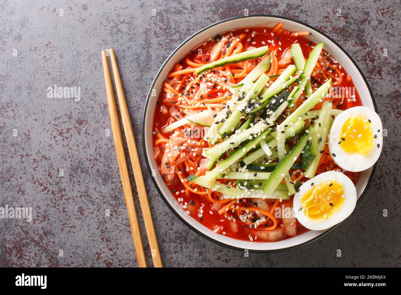 Nouilles froides épicées coréennes Bibim Guksu closeup dans le bol sur la table. Vue horizontale du dessus Banque D'Images