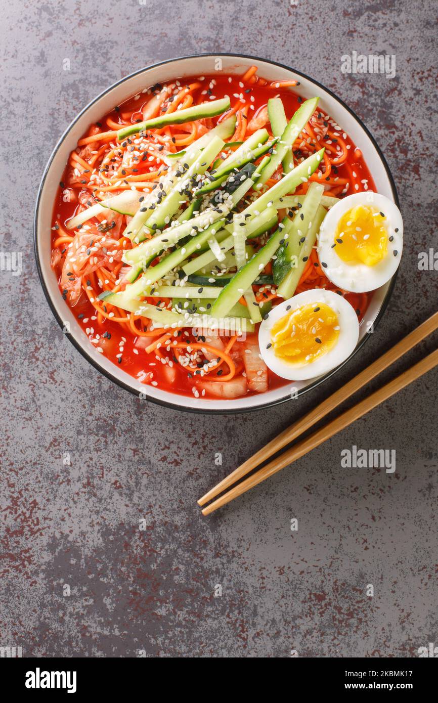 Salade de nouilles alimentaires coréennes Bibim guksu dans un bol noir sur la table de clôture. Vue verticale du dessus Banque D'Images