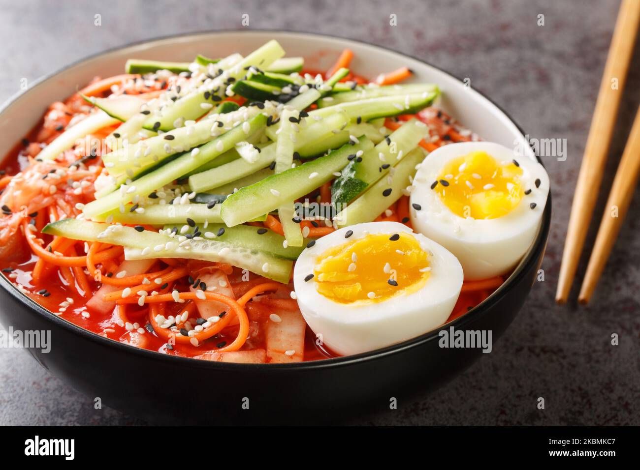 Nouilles froides épicées coréennes Bibim Guksu closeup dans le bol sur la table. Horizontale Banque D'Images