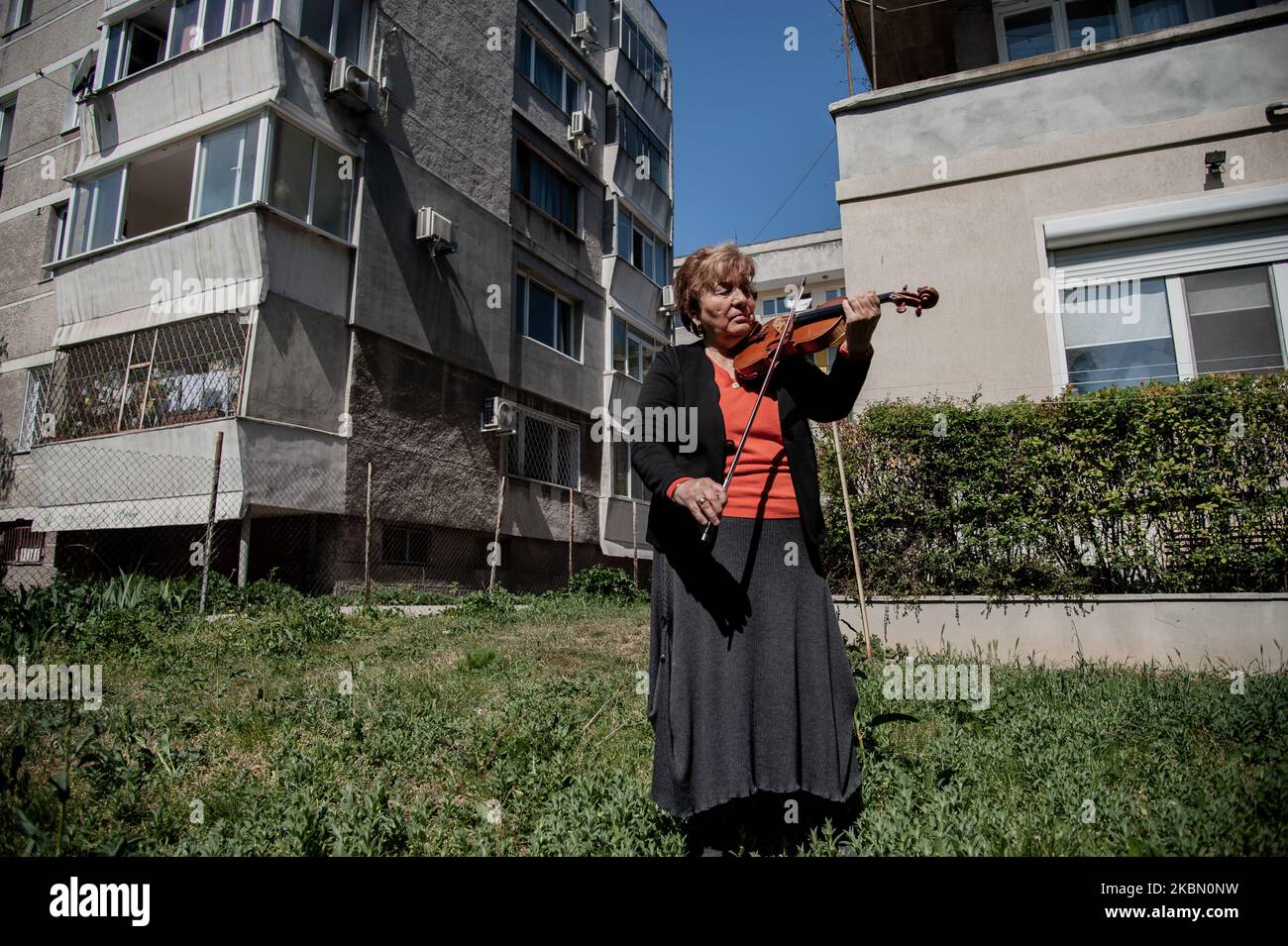 Une femme âgée joue le violon devant l'immeuble où elle vit pour soulever les esprits de ses voisins pendant la quarantaine. GRETA Burova, 80 ans, est interprète et professeur de violon à l'École nationale des Arts Dobri Hristov de Varna, Bulgarie. Elle dit que la musique est la langue qu'elle parle le mieux, elle joue pour ses voisins chaque jour pour apporter la joie dans leur vie, Varna, Bulgarie sur 27 avril 2020 (photo de Hristo Rusev/NurPhoto) Banque D'Images