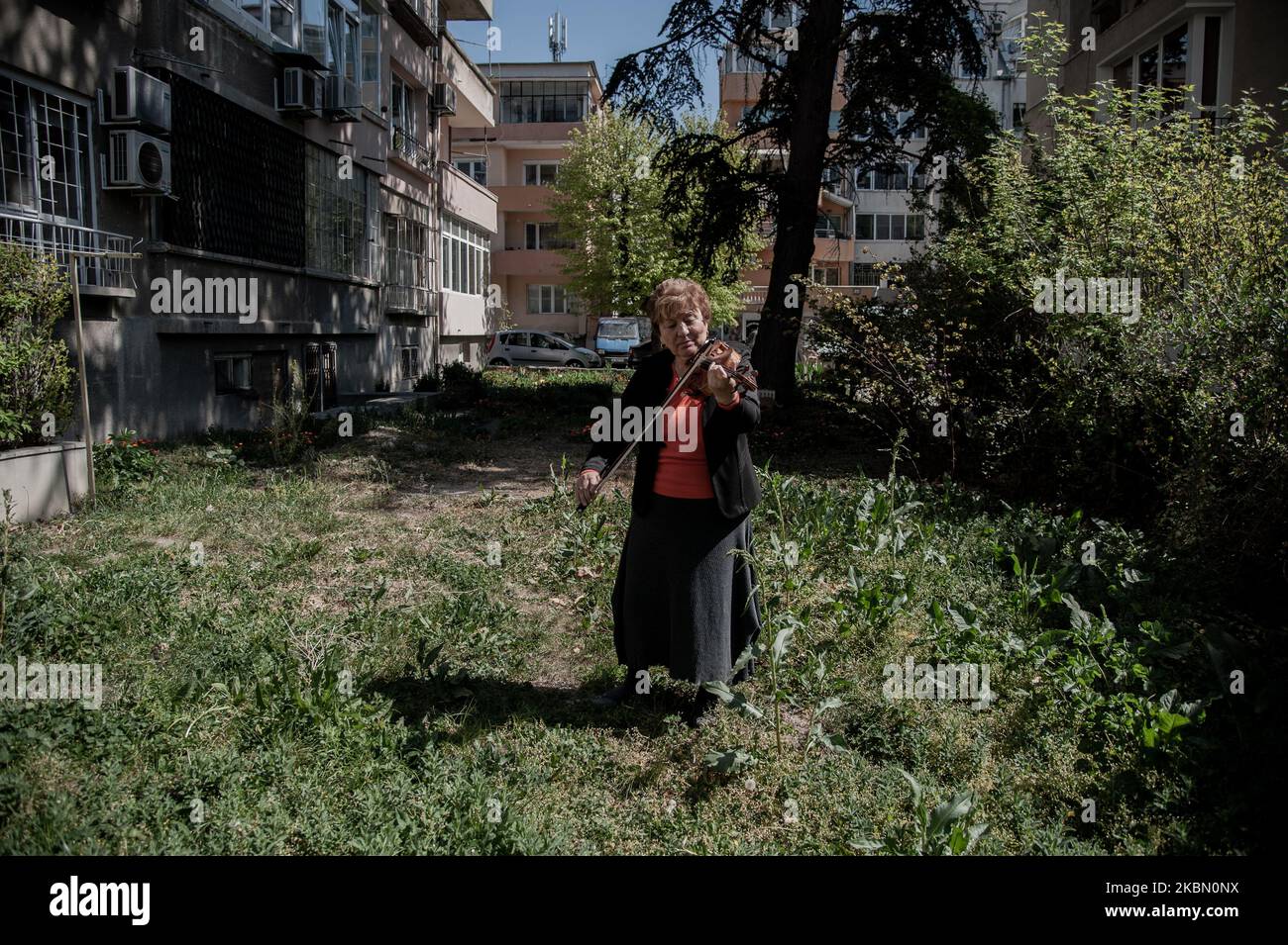 Une femme âgée joue le violon devant l'immeuble où elle vit pour soulever les esprits de ses voisins pendant la quarantaine. GRETA Burova, 80 ans, est interprète et professeur de violon à l'École nationale des Arts Dobri Hristov de Varna, Bulgarie. Elle dit que la musique est la langue qu'elle parle le mieux, elle joue pour ses voisins chaque jour pour apporter la joie dans leur vie, Varna, Bulgarie sur 27 avril 2020 (photo de Hristo Rusev/NurPhoto) Banque D'Images