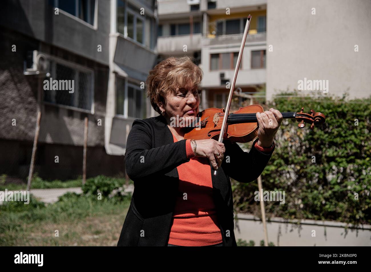 Une femme âgée joue le violon devant l'immeuble où elle vit pour soulever les esprits de ses voisins pendant la quarantaine. GRETA Burova, 80 ans, est interprète et professeur de violon à l'École nationale des Arts Dobri Hristov de Varna, Bulgarie. Elle dit que la musique est la langue qu'elle parle le mieux, elle joue pour ses voisins chaque jour pour apporter la joie dans leur vie, Varna, Bulgarie sur 27 avril 2020 (photo de Hristo Rusev/NurPhoto) Banque D'Images