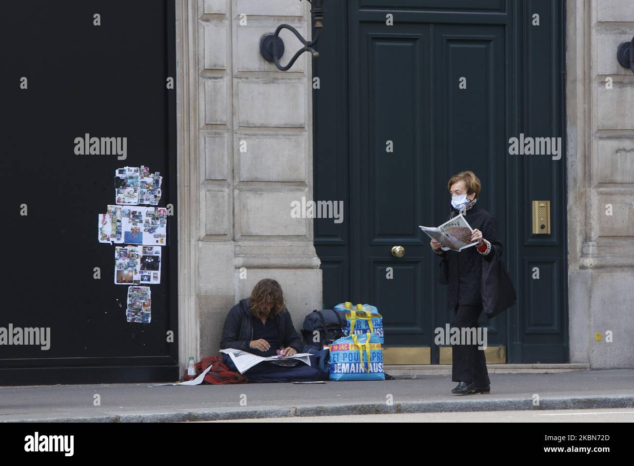Une femme lit son journal et marche sur un front un sans-abri qui lit son journal à Saint Germain des Prés à Paris, comme un verrouillage est imposé pour ralentir le taux de la maladie du coronavirus (COVID-19) en France, 2 mai 2020. (Photo de Mehdi Taamallah / NurPhoto) (photo de Mehdi Taamallah / NurPhoto) Banque D'Images