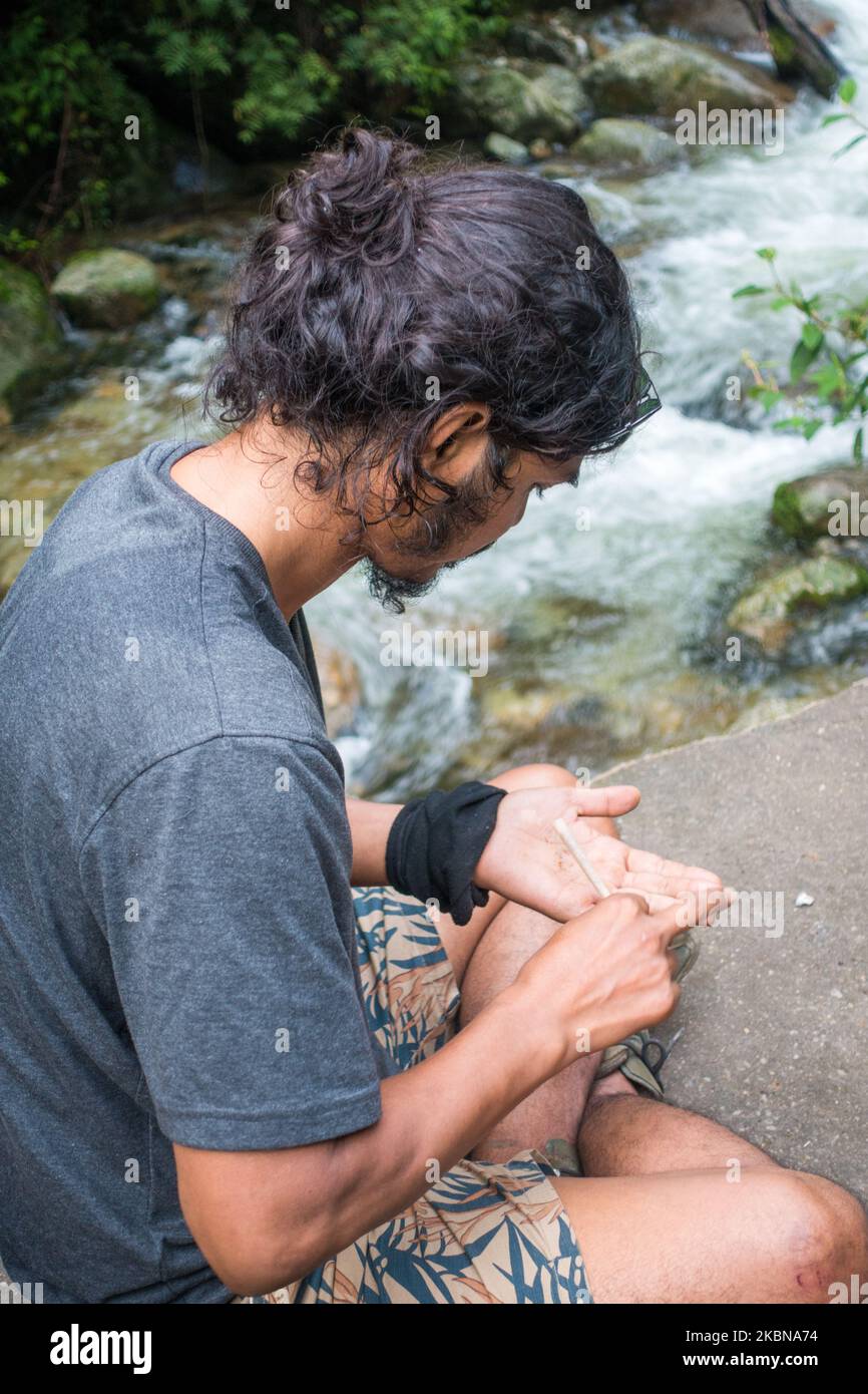 14 juillet 2022, Himachal Pradesh Inde.. Pose latérale d'un jeune homme avec un petit pain roulant un joint de mauvaise herbe dans les collines de l'Himalaya. Banque D'Images