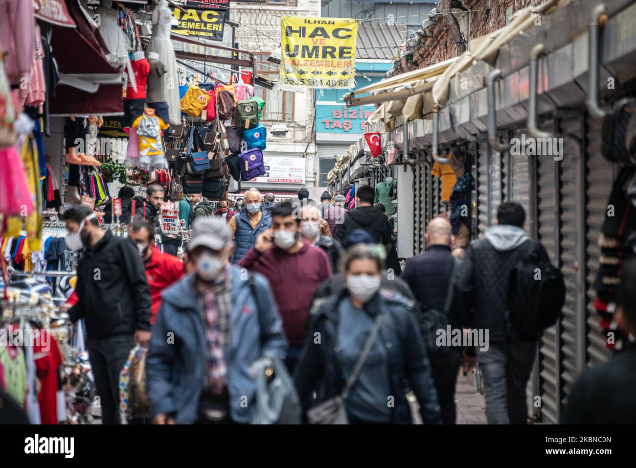 Le 5 mai 2020, les résidents d'Istanbul, le centre de la pandémie de Covid-19 en Turquie, portaient des masques lorsqu'ils magasinaient dans le quartier historique d'Eminonu, où de nombreux magasins restent fermés en raison des restrictions imposées pour enrayer la propagation du coronavirus. De telles précautions pèsent lourdement sur l'économie turque et sur la lire turque, qui est tombée à sa plus faible valeur depuis la crise financière de cette semaine. Ci-dessus, les acheteurs turcs portant des masques marchent sous un drapeau turc dans une zone de marché bondée dans le quartier Eminonu de Fatih, Istanbul. (Photo de Diego Cupolo/NurPhoto) Banque D'Images