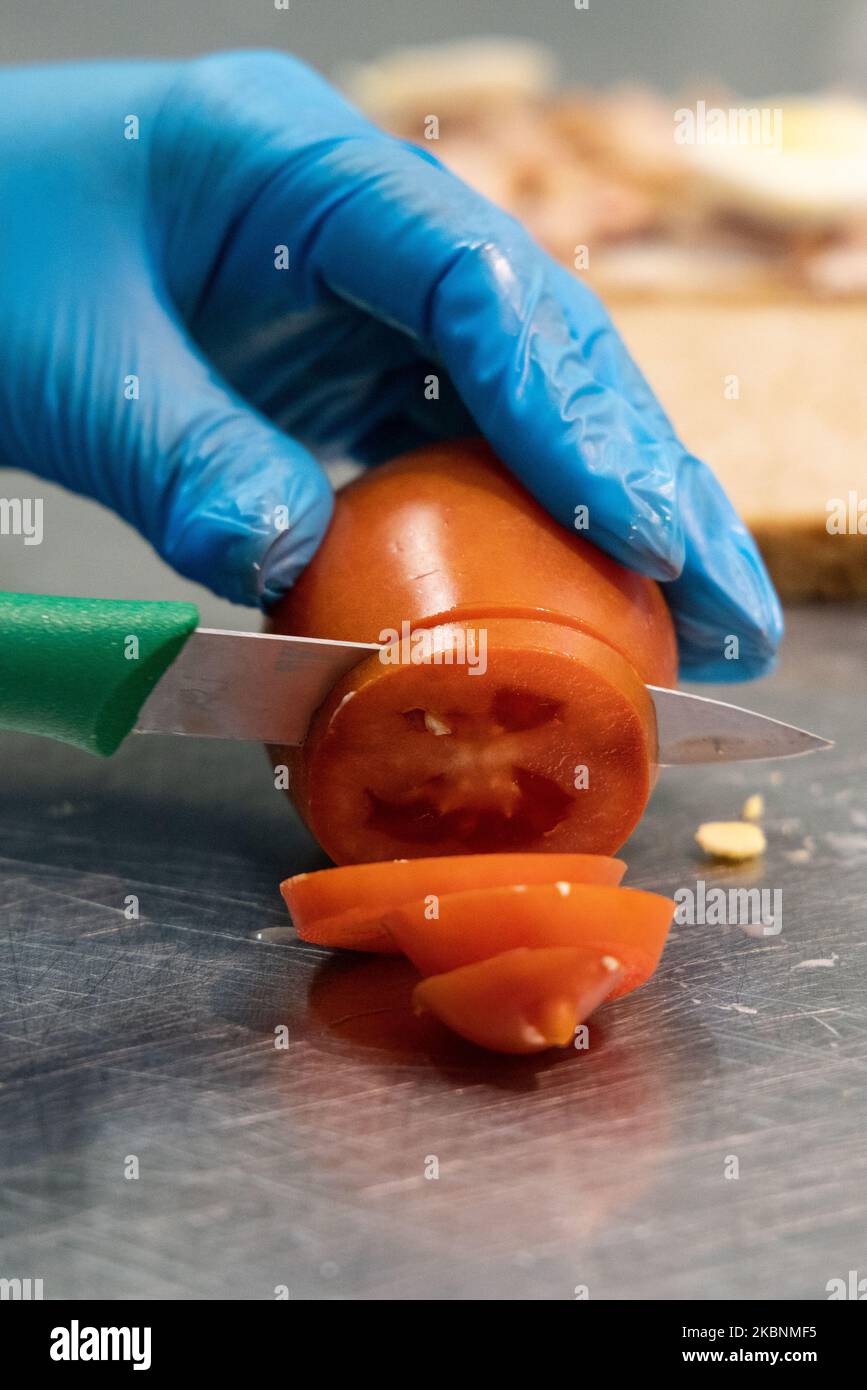 Comptoir déli frais dans un hypermarché de Cora. Employé préparant un sandwich avec du pain coupé en tranches. Ici, couper une tomate Banque D'Images