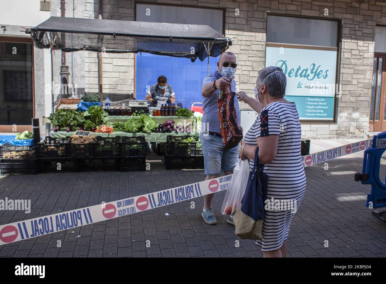 Un petit marchand remet à un client son ordre qu'elle avait laissé en dépôt par un cordon de police pour maintenir un double sens parmi les piétons sur le marché hebdomadaire à Norenia, , à Norena, Espagne, sur 31 mai, 2020. (Photo d'Alvaro Fuente/NurPhoto) Banque D'Images