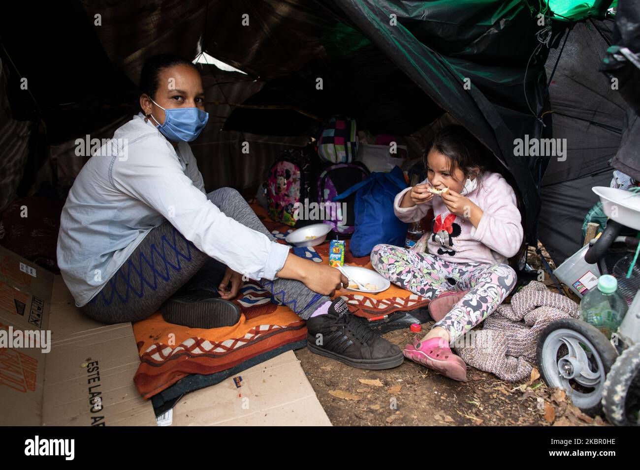 Une mère et une fille se sont assises dans leur tente avec une partie de la nourriture qui a été donnée au camp de migrants de fortune le long de l'autoroute quittant Bogota, Colombie le 5th juin 2020. Environ 600 000 personnes sont ici en attente du gouvernement pour les aider à retourner au Venezuela. Sans électricité, eau ou système sanitaire, ils attendent tout type d'aide. (Photo de Keoma Zec/NurPhoto) Banque D'Images