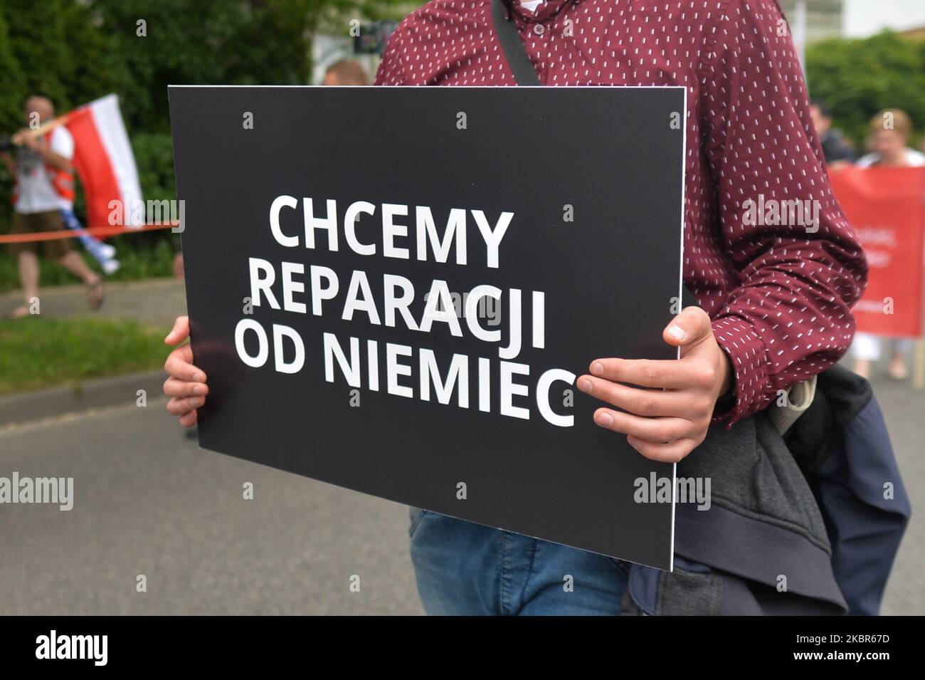 Un homme porte le signe « nous voulons des réparations de guerre de l'Allemagne » lors d'une marche pour commémorer le 80th anniversaire du premier transport de 728 prisonniers polonais au camp allemand de la mort d'Auschwitz. En 2006, le Sejm polonais (Parlement) a voté pour faire de 14 juin la Journée nationale du souvenir des victimes des camps allemands de concentration et d'extermination nazis. Aujourd'hui, le musée d'Auschwitz a été fermé à cause de la visite du président polonais Andrzej Duda. Seuls quelques visiteurs qui avaient fait une demande à l'avance ont été autorisés à entrer. Sur 14 juin 2020, Oswiecim, Pologne. (Photo par Artur Widak/NurPhoto) Banque D'Images