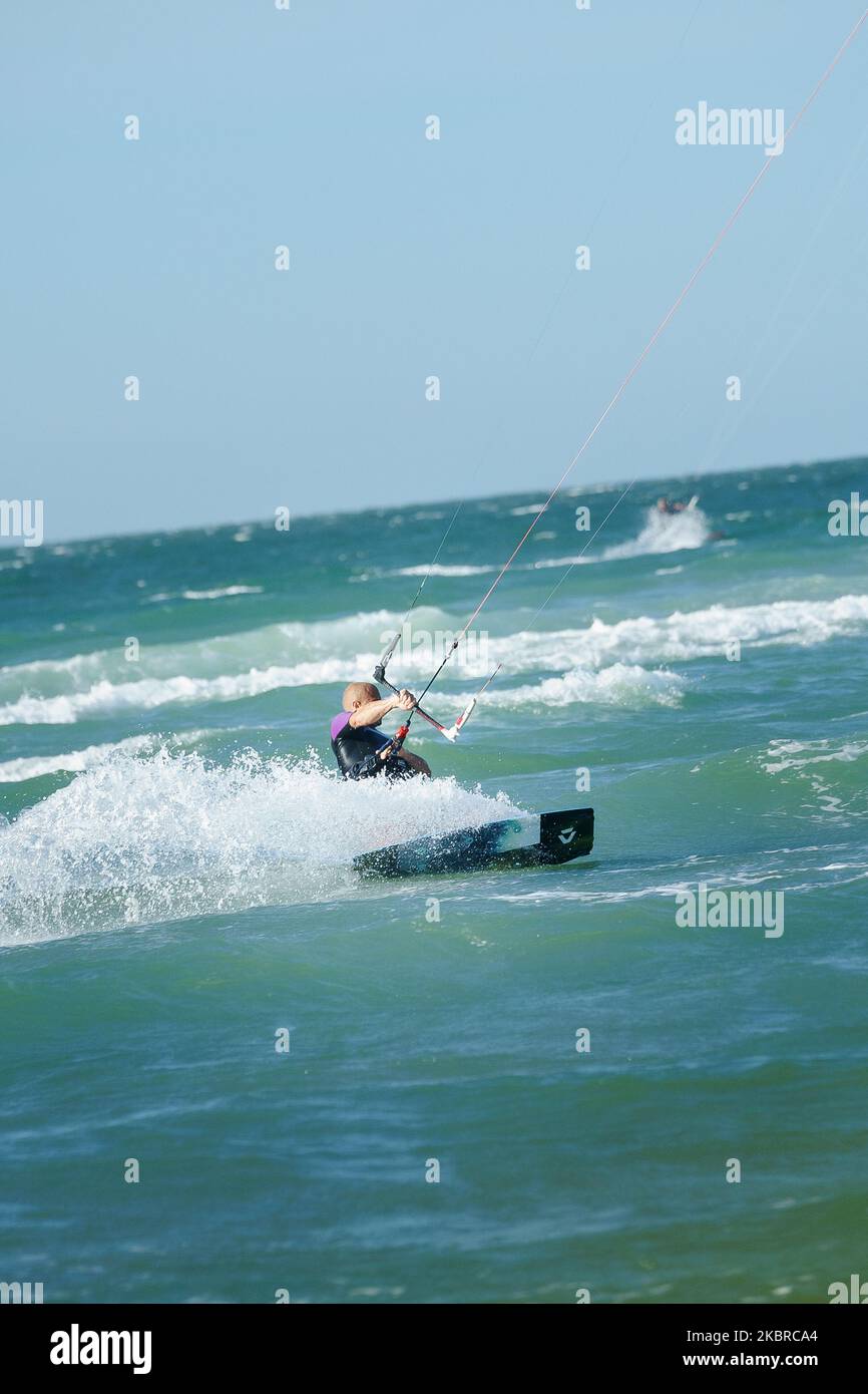 Les gens aiment faire du kite surf dans un costume de protection uv au soleil lors d'une journée ensoleillée au bord de la mer ou au camp de kitesurf sur la rive de l'océan. Sports nautiques adrénaline f Banque D'Images