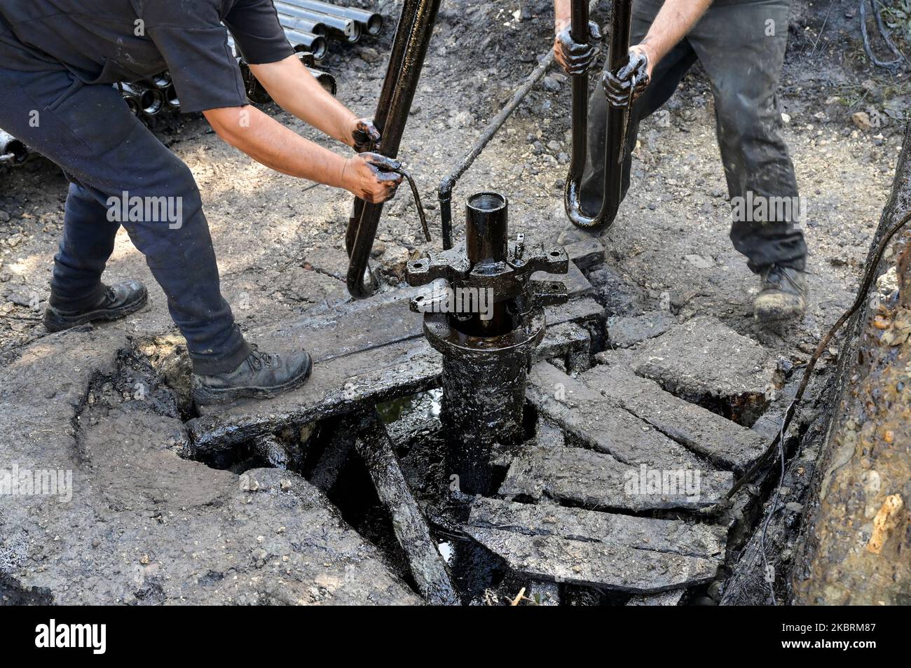 ALBANIE, Kuçova, nommé ville de Staline à partir de 1950 to1991, champ de pétrole brut et pompe de forage de l'ère communiste, toujours en fonctionnement et polluant l'environnement, ouvrier avec le tuyau de forage / ALBANIEN, Kucova, von 1950 bis 1991 Qyteti Staline, Stalinstadt, Erdoelfoerderung, alte Oelfoerderpe, die heute noch pumzur, Özörsind, Betrieb pumzur Beiter mit Bohrgestänge Banque D'Images