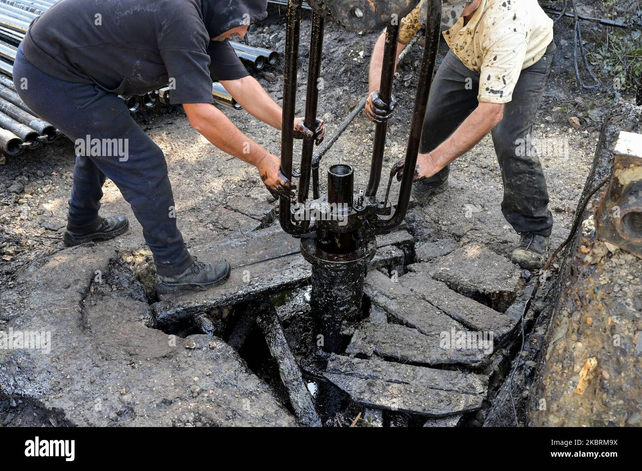 ALBANIE, Kuçova, nommé ville de Staline à partir de 1950 to1991, champ de pétrole brut et pompe de forage de l'ère communiste, toujours en fonctionnement et polluant l'environnement, ouvrier avec le tuyau de forage / ALBANIEN, Kucova, von 1950 bis 1991 Qyteti Staline, Stalinstadt, Erdoelfoerderung, alte Oelfoerderpe, die heute noch pumzur, Özörsind, Betrieb pumzur Beiter mit Bohrgestänge Banque D'Images