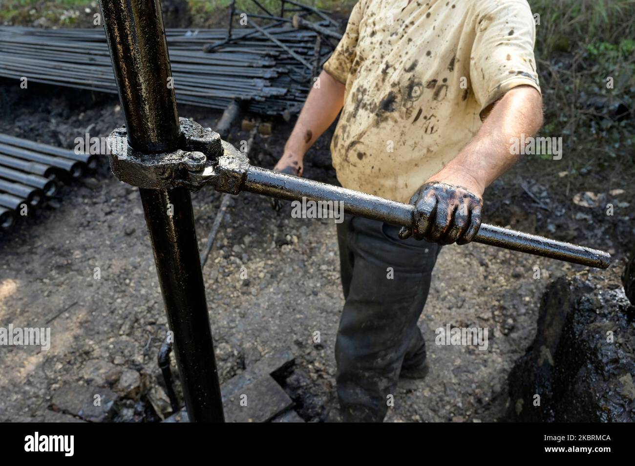 ALBANIE, Kuçova, nommé ville de Staline à partir de 1950 to1991, champ de pétrole brut et pompe de forage de l'ère communiste, toujours en fonctionnement et polluant l'environnement, ouvrier avec le tuyau de forage / ALBANIEN, Kucova, von 1950 bis 1991 Qyteti Staline, Stalinstadt, Erdoelfoerderung, alte Oelfoerderpe, die heute noch pumzur, Özörsind, Betrieb pumzur Beiter mit Bohrgestänge Banque D'Images