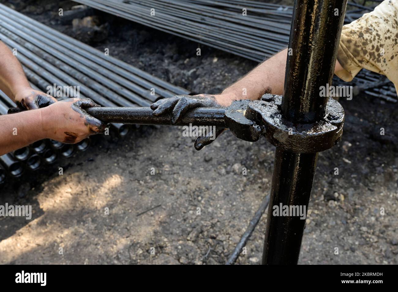 ALBANIE, Kuçova, nommé ville de Staline à partir de 1950 to1991, champ de pétrole brut et pompe de forage de l'ère communiste, toujours en fonctionnement et polluant l'environnement, ouvrier avec le tuyau de forage / ALBANIEN, Kucova, von 1950 bis 1991 Qyteti Staline, Stalinstadt, Erdoelfoerderung, alte Oelfoerderpe, die heute noch pumzur, Özörsind, Betrieb pumzur Beiter mit Bohrgestänge Banque D'Images