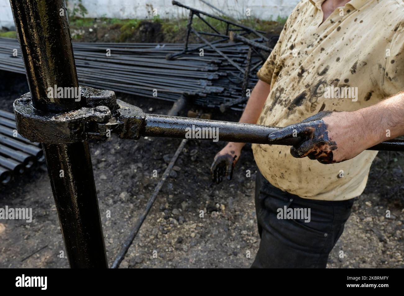 ALBANIE, Kuçova, nommé ville de Staline à partir de 1950 to1991, champ de pétrole brut et pompe de forage de l'ère communiste, toujours en fonctionnement et polluant l'environnement, ouvrier avec le tuyau de forage / ALBANIEN, Kucova, von 1950 bis 1991 Qyteti Staline, Stalinstadt, Erdoelfoerderung, alte Oelfoerderpe, die heute noch pumzur, Özörsind, Betrieb pumzur Beiter mit Bohrgestänge Banque D'Images
