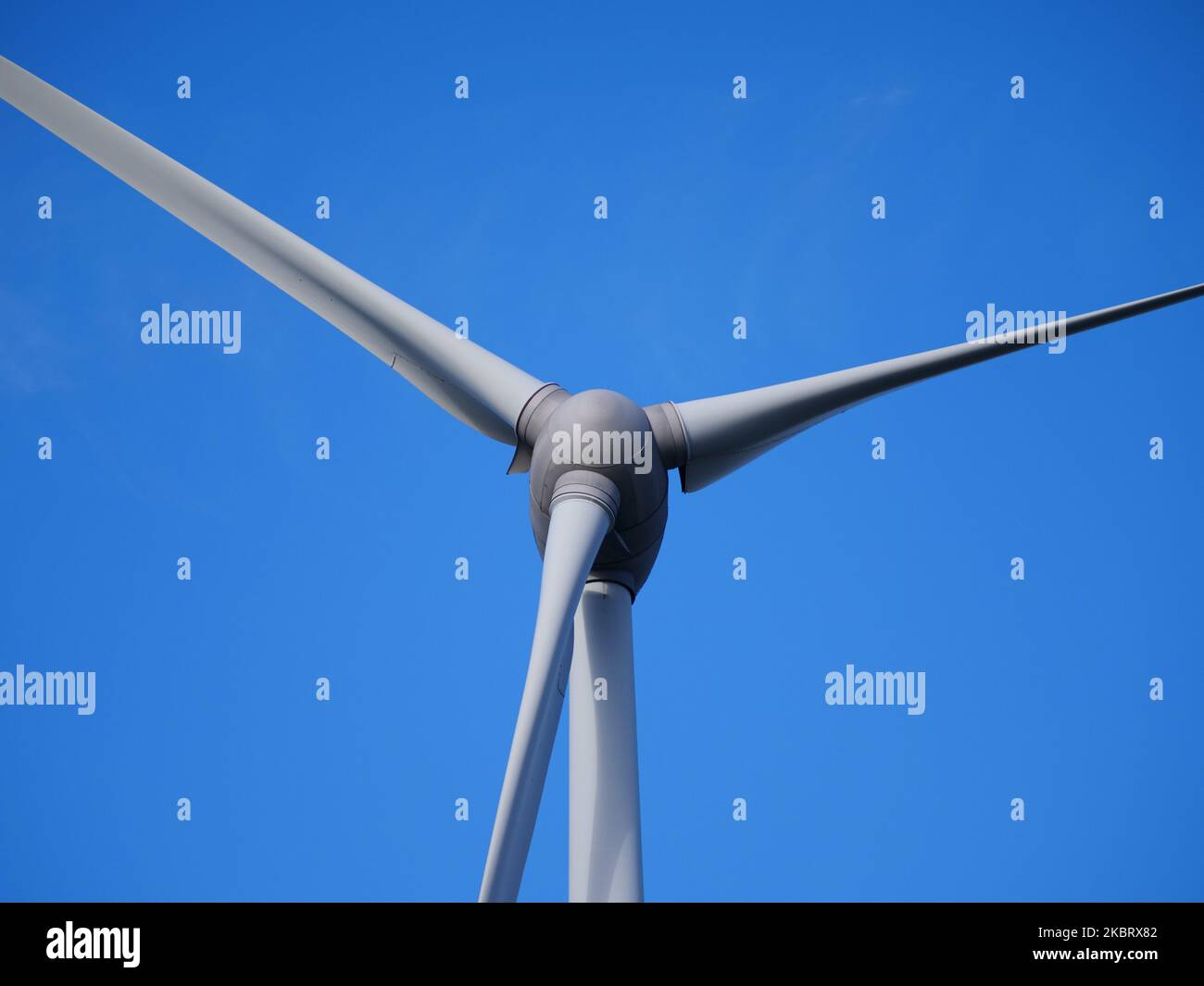 Éolienne en gros plan avec les trois pales contre un ciel bleu en arrière-plan Banque D'Images
