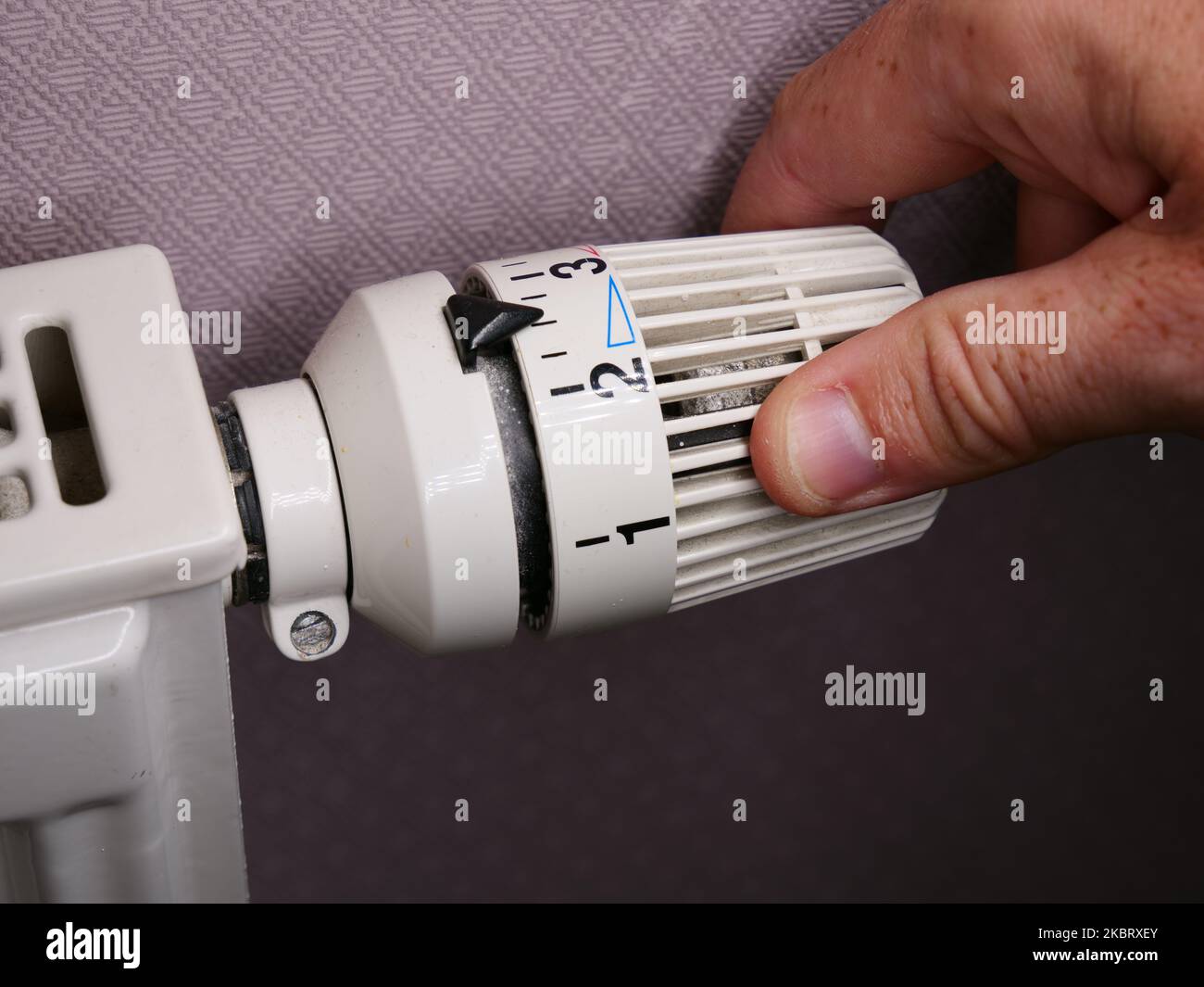 Augmentation des coûts de chauffage dans la crise : l'homme règle la température à la maison avec le thermostat de chauffage pour économiser l'énergie, de près à la main Banque D'Images