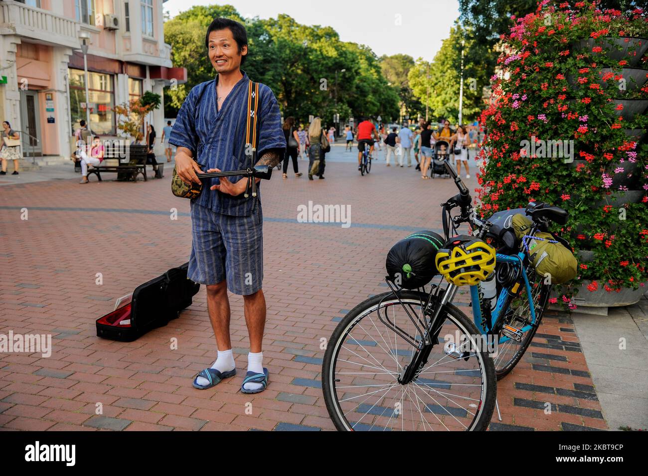 Takashi est un homme de 40 ans d'Okinawa, au Japon. Il y a un an, il était chef de sushi dans sa ville natale. Maintenant, il joue sanshi - instrument traditionnel d'Okinawa dans les rues de Varna, Bulgarie, à plus de 15 000 km de la maison. L'année dernière, après avoir divorcé avec sa femme, Takashi a décidé de prendre le temps de faire ce qu'il voulait toujours faire - voyager dans le monde, rencontrer de nouvelles personnes et partager avec eux des valeurs japonaises traditionnelles - comme chérir notre nature, nos langues et les autres. Il voyage principalement en vélo. Il utilise parfois des trains ou des ferries, mais jamais des avions - ils ne sont pas écologiques mais Banque D'Images