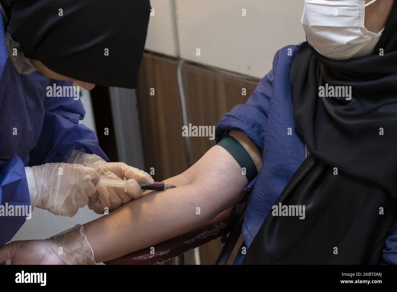 Un technicien de laboratoire portant une combinaison de protection procède à l'échantillonnage d'une femme qui se présente dans un laboratoire de virologie pour effectuer un nouveau test d'anticorps du coronavirus (Covid-19) dans le centre de Téhéran, en Iran, sur 8 juin 2020. (Photo de Morteza Nikoubazl/NurPhoto) Banque D'Images