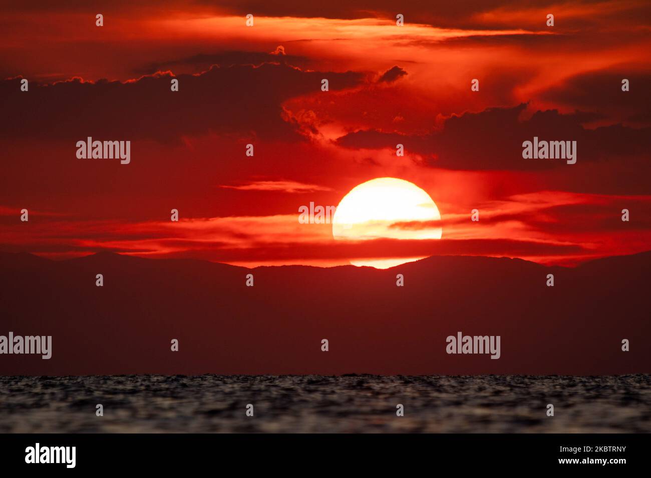 Coucher de soleil sur la plage de Paralia Epanomi en Grèce sur 16 juillet 2020. Epanomi est situé près de la destination touristique populaire de Chalkidiki et de la ville de Thessalonique, touchant le sable doré de la Méditerranée avec l'eau transparente du golfe Thermaikos et de la mer Égée. Le soleil se couche derrière la mer et les montagnes créant des couleurs chaudes de l'heure magique dans le ciel. (Photo de Nicolas Economou/NurPhoto) Banque D'Images