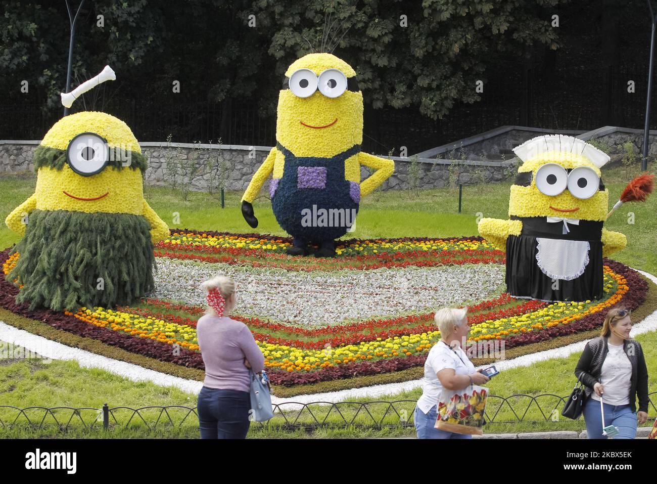 Les visiteurs se promongent devant les personnages de dessins animés géants Minions faits de fleurs lors du spectacle de fleurs « Cartoon-Land » qui s'ouvre à Kiev, en Ukraine, le 14 août 2020. Plus de 300 mille fleurs ont été utilisées pour créer des personnages de dessins animés géants à partir de dessins célèbres. (Photo par STR/NurPhoto) Banque D'Images