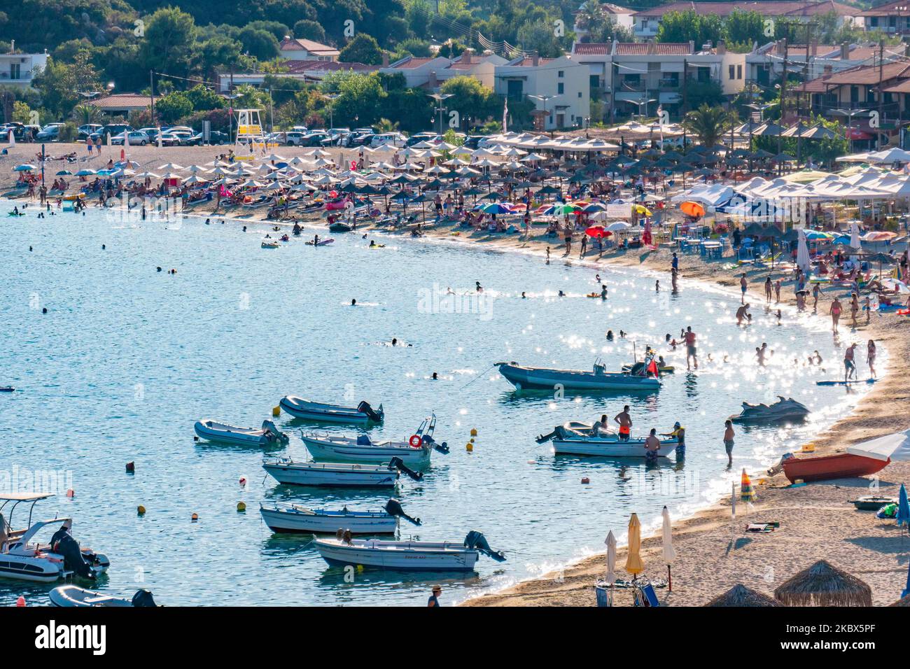 Vue panoramique sur la plage de Kalamitsi. Foule de touristes à la célèbre et populaire plage de Kalamitsi située à la pointe sud de la péninsule de Sithonia à Chalkidiki dans le nord de la Grèce. Les gens s'amusent à la plage en Grèce car ils se détendent à l'ombre des parasols, plongée en apnée, plongée sous-marine, natation dans les eaux cristallines tropicales exotiques, sports nautiques, location de bateaux, prendre un verre dans les bars de la plage ou prendre un bain de soleil sur le sable doré et profiter de la vie sur la plage sous le ciel bleu ensoleillé. Il y a une petite île également située près de la rive. Le gouvernement local est addi Banque D'Images