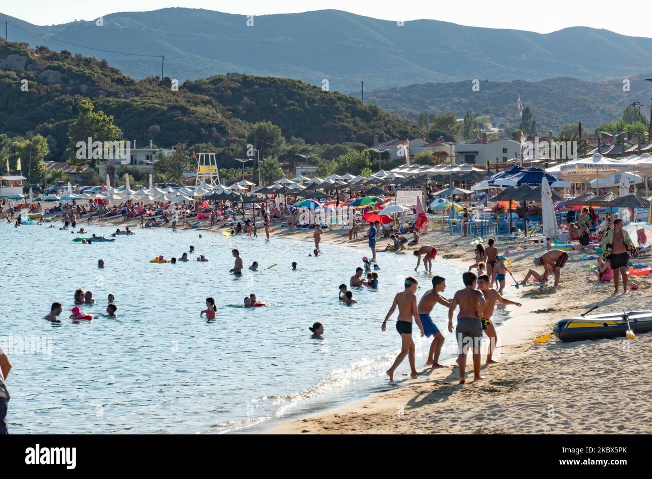 Vue panoramique sur la plage de Kalamitsi. Foule de touristes à la célèbre et populaire plage de Kalamitsi située à la pointe sud de la péninsule de Sithonia à Chalkidiki dans le nord de la Grèce. Les gens s'amusent à la plage en Grèce car ils se détendent à l'ombre des parasols, plongée en apnée, plongée sous-marine, natation dans les eaux cristallines tropicales exotiques, sports nautiques, location de bateaux, prendre un verre dans les bars de la plage ou prendre un bain de soleil sur le sable doré et profiter de la vie sur la plage sous le ciel bleu ensoleillé. Il y a une petite île également située près de la rive. Le gouvernement local est addi Banque D'Images